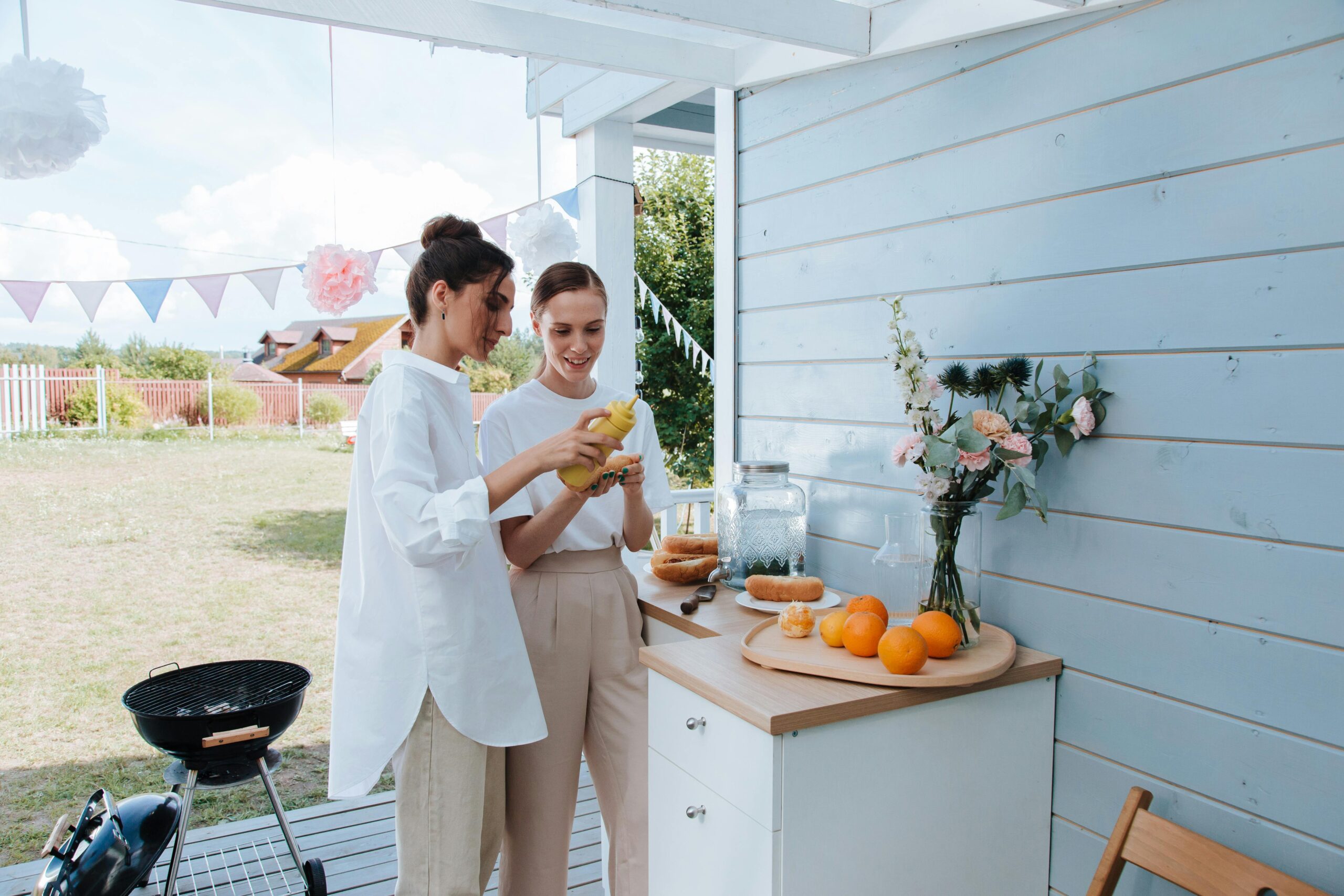 Two women preparing food outdoors for a summer barbecue celebration.