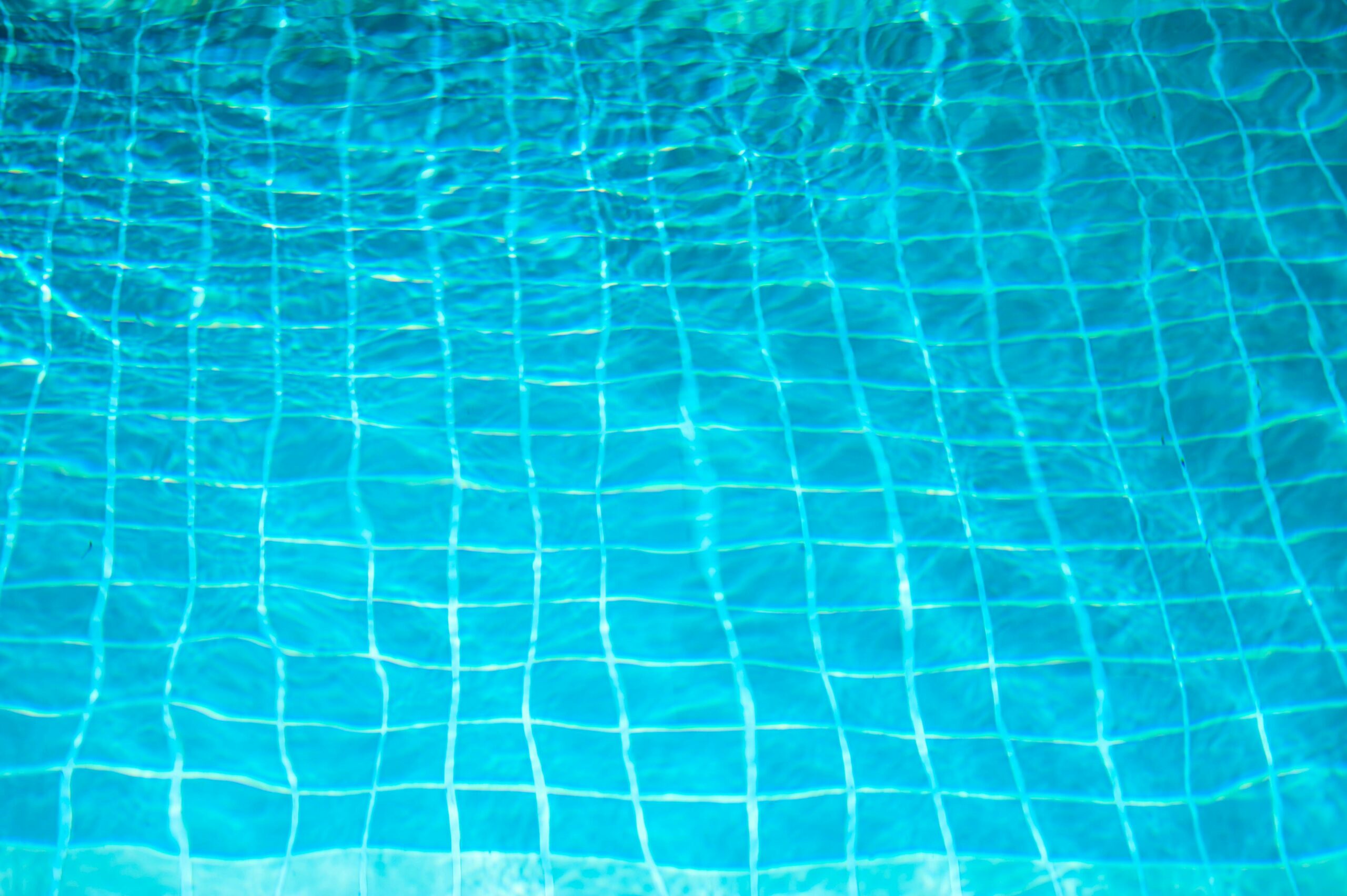 A vibrant image of blue swimming pool tiles with shimmering water reflections.