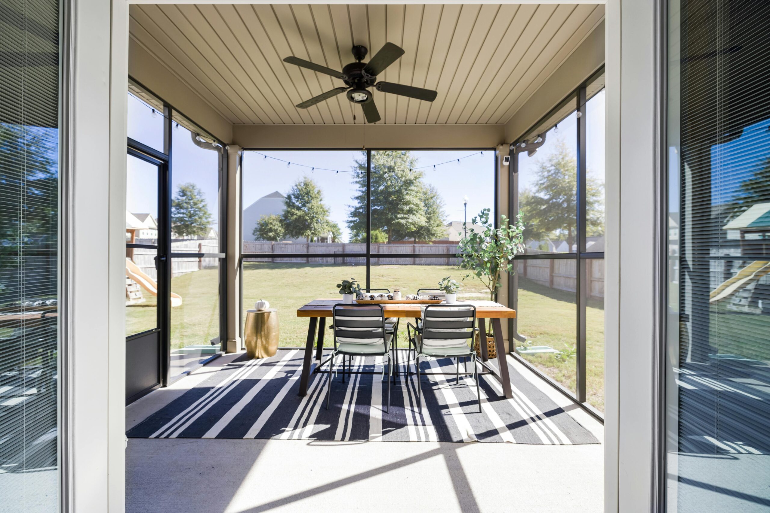 A bright and inviting terrace with dining table and chairs, overlooking a sunny garden.