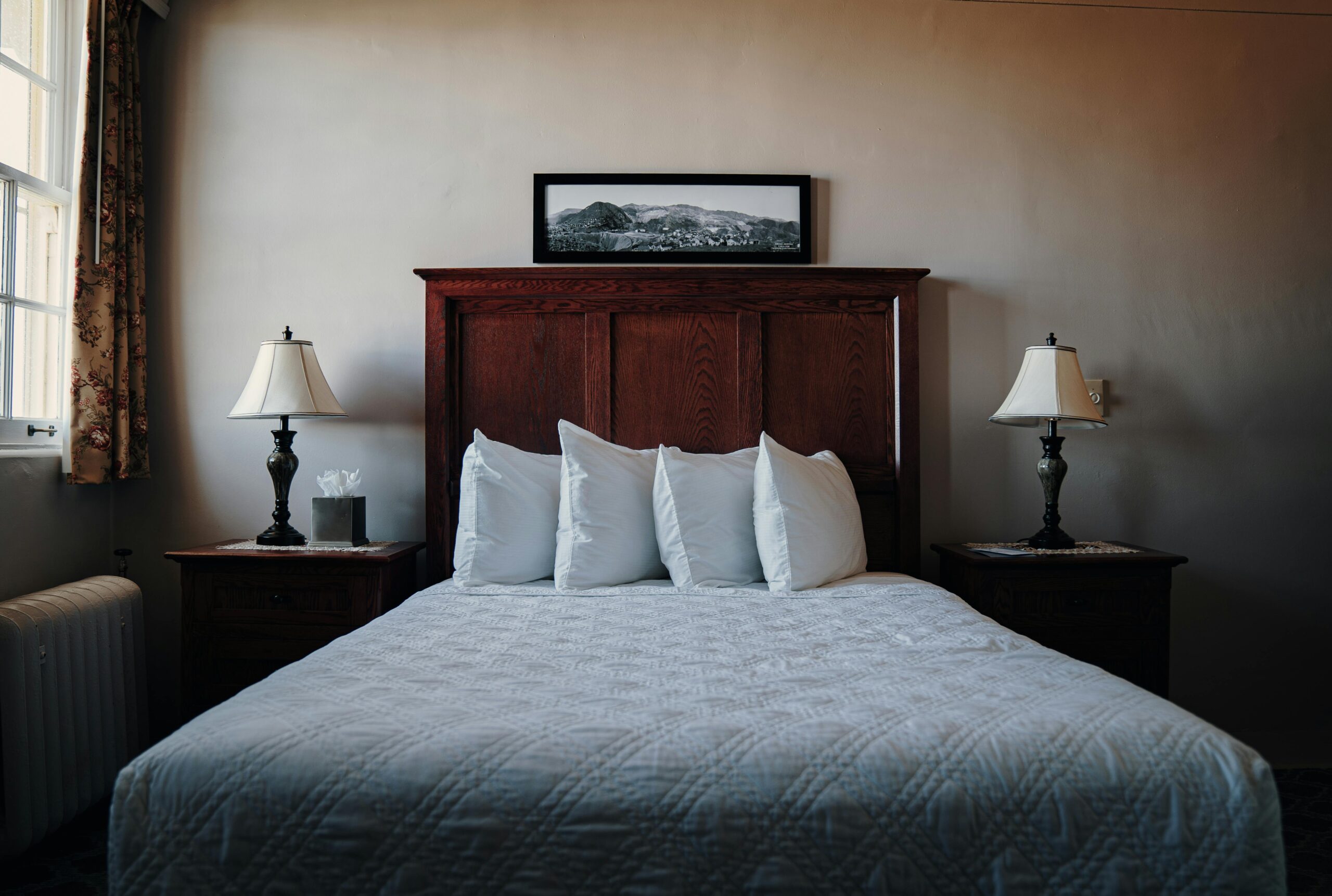 A beautifully arranged bedroom in Jerome, AZ, showcasing a wooden headboard, lamps, and a cozy bed.