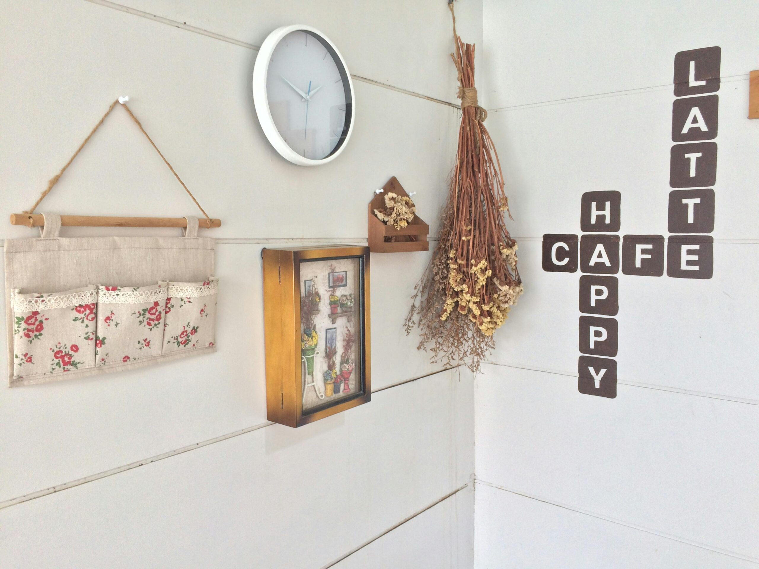 Modern café corner with minimalist decor, wall clock, and dried flowers.