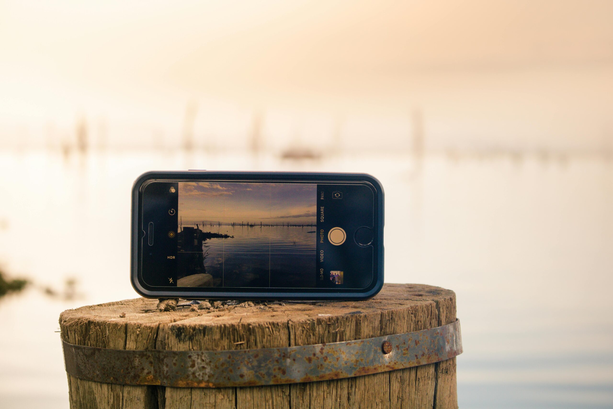 A smartphone captures a serene lake at sunset, reflecting tranquility and natural beauty.