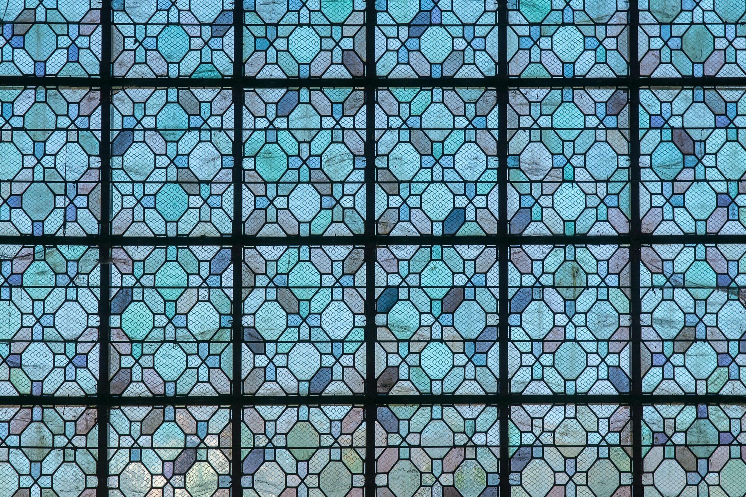 Intricate stained glass window pattern featuring blue geometric designs, perfect for religious or architectural themes.