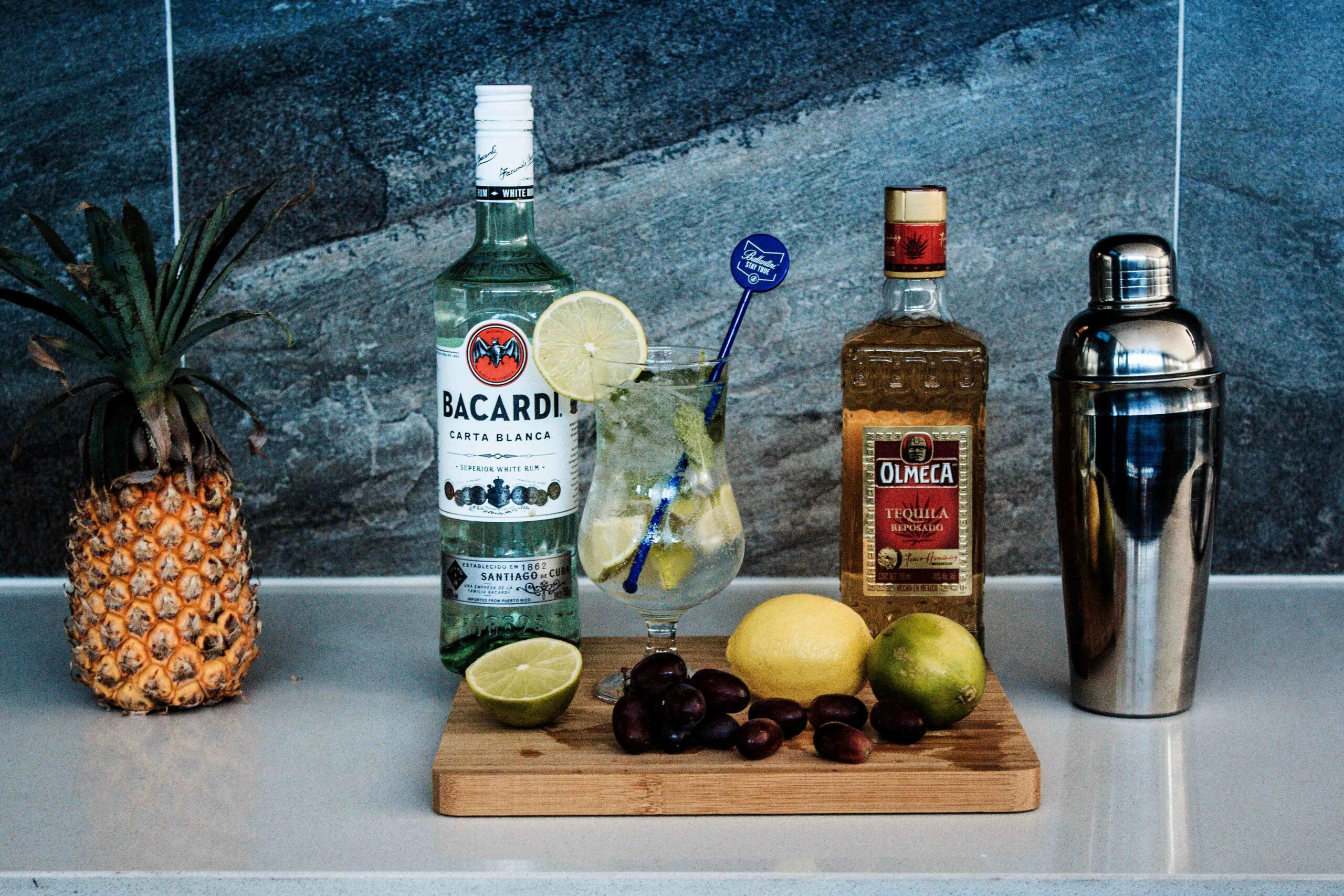 A vibrant cocktail with tropical fruits, rum, and tequila displayed on a countertop.
