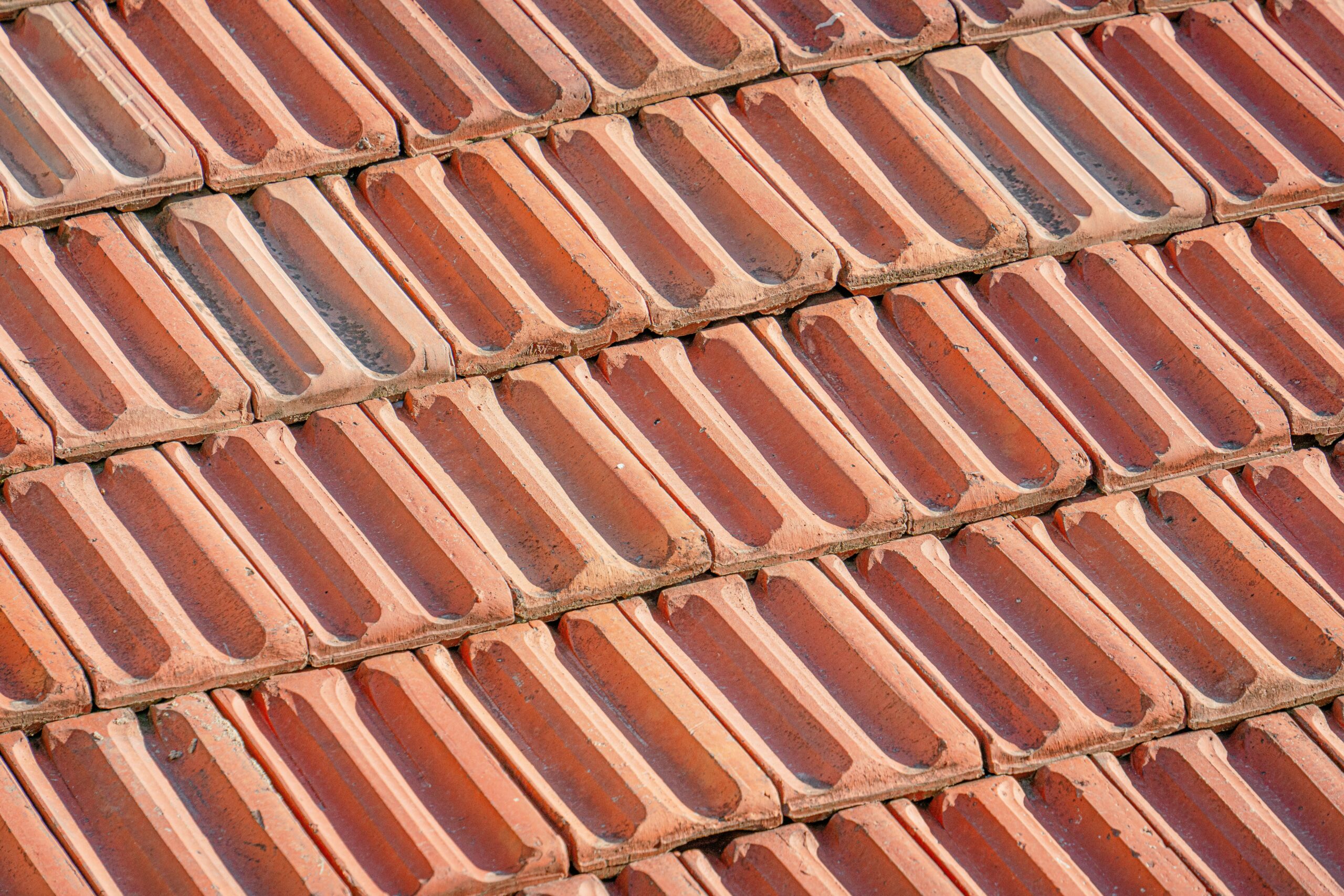 Detailed view of overlapping terracotta tiles forming a textured rooftop surface.