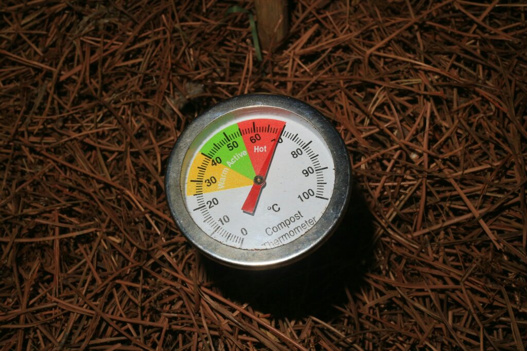 Close-up of a compost thermometer in soil, temperature in active range.