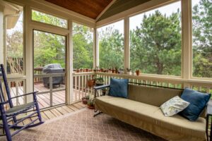 Relaxing screened porch with couch, plants, and outdoor greenery view.