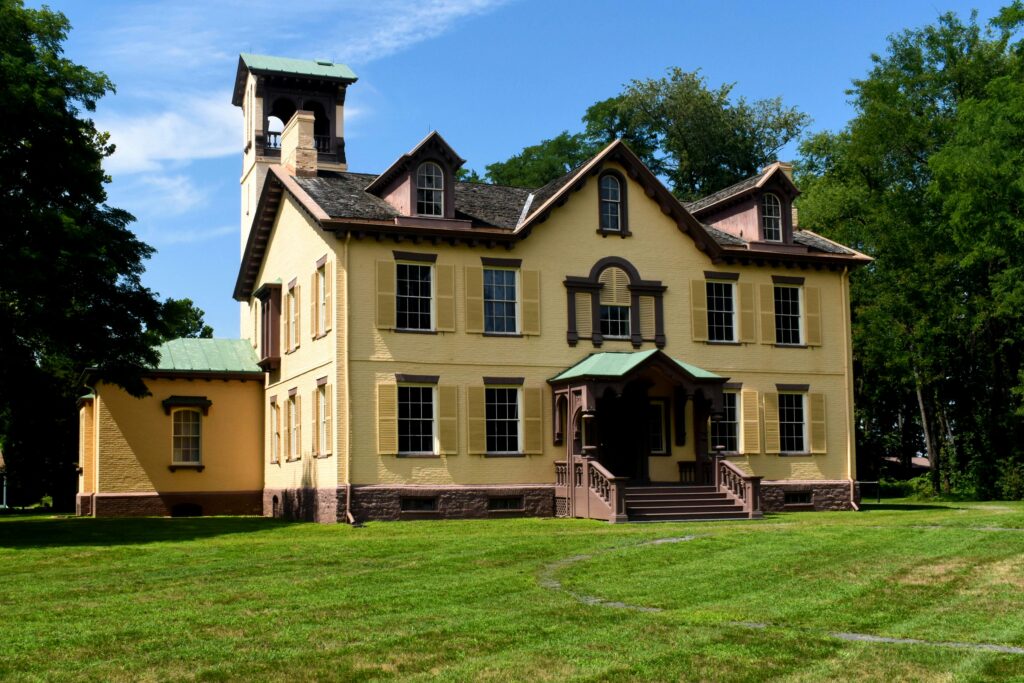 Historic Lindenwald mansion in Kinderhook, NY, surrounded by green lawn under clear skies.