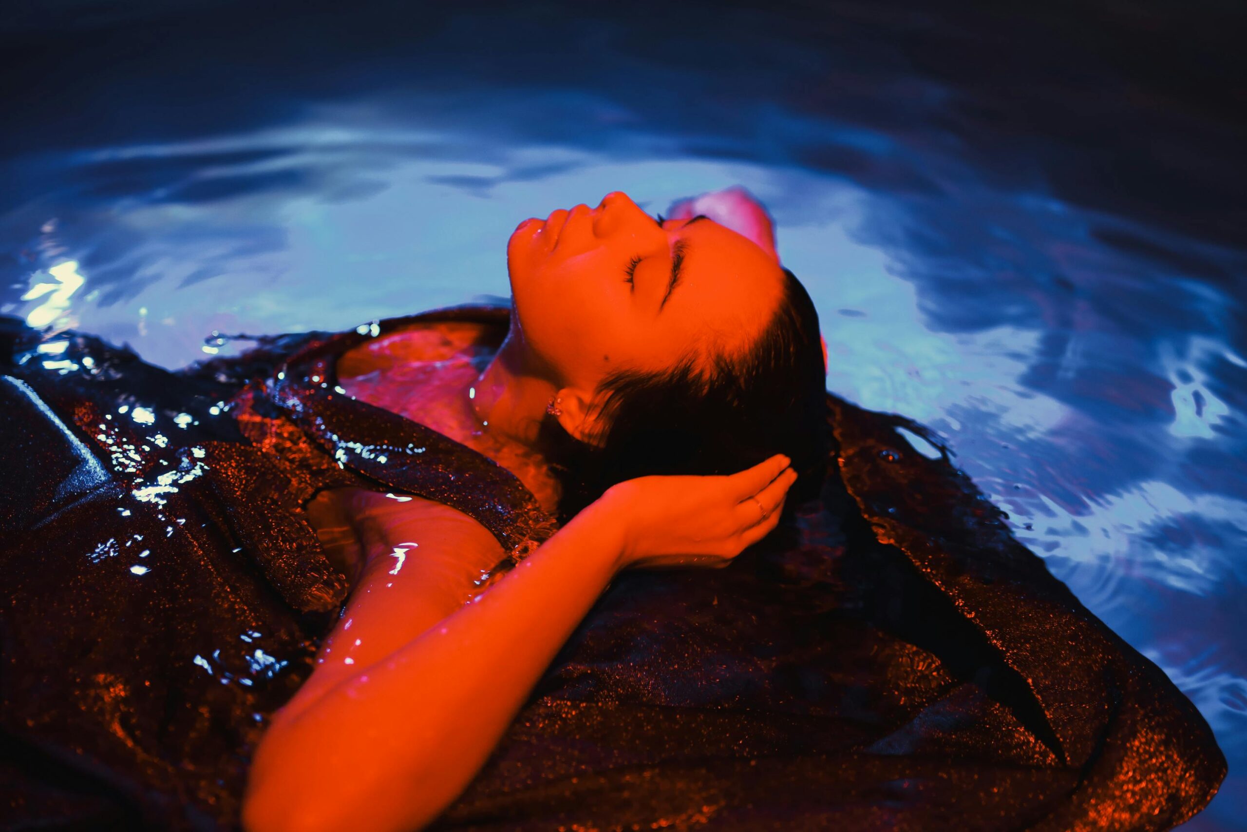 A woman submerged in water with artistic lighting creating a captivating mood.