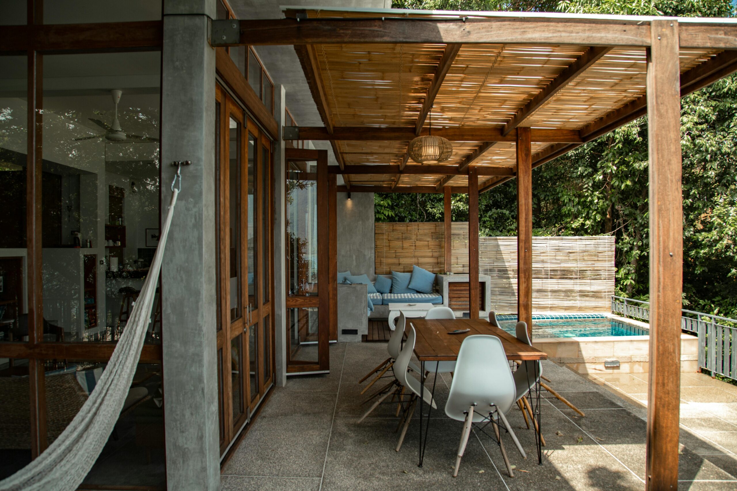 A stylish outdoor patio with wooden pergola and swimming pool, perfect for relaxation.