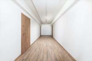 Clean white hallway with wooden flooring and contemporary doors, showcasing minimalism.