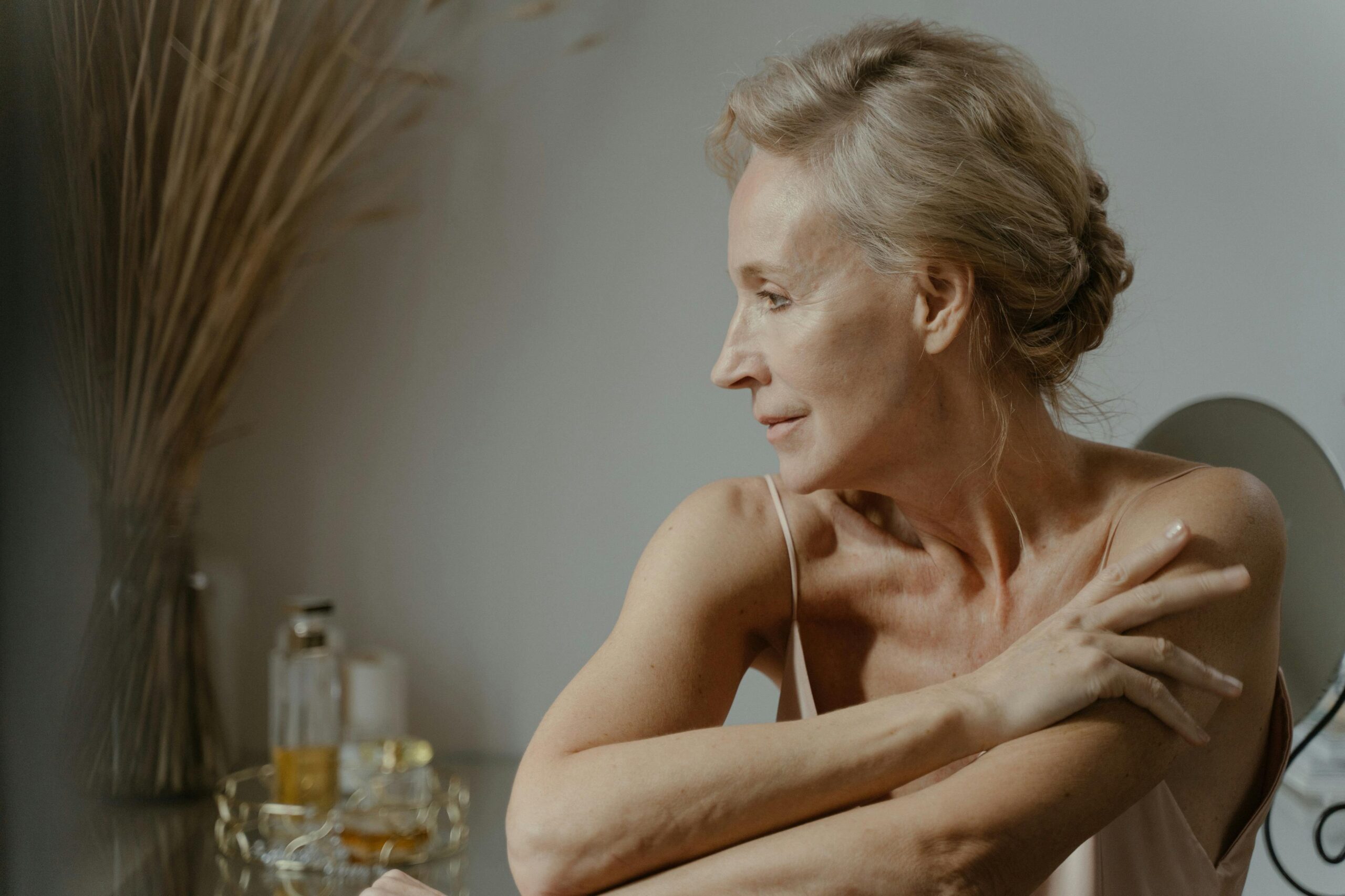 A serene and elegant portrait of a mature woman in a relaxed pose indoors, showcasing natural beauty.